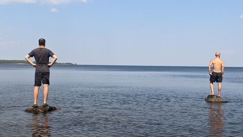 Rear view of man standing in sea against sky