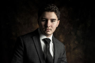 Portrait of young man against black background