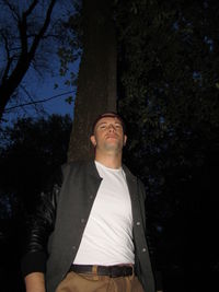 Low angle view of man standing on tree trunk against plants