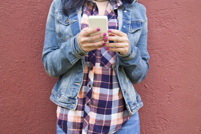 Young woman with mobile phone on the wall