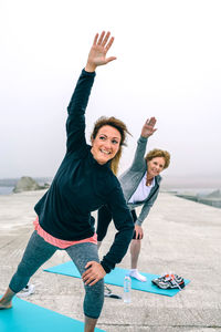 Female friends doing yoga on walkway