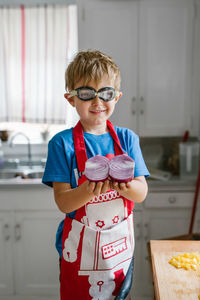 Boy holding halved onion in kitchen at home