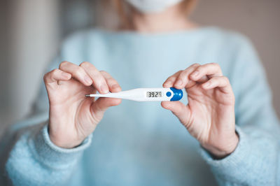 Woman holding thermometer check high temperature closeup. illness concept. coronavirus symptoms.