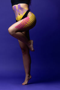Low section of woman standing against blue background