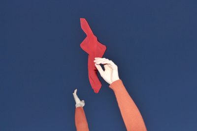 Close-up of hand holding red fabric against blue background