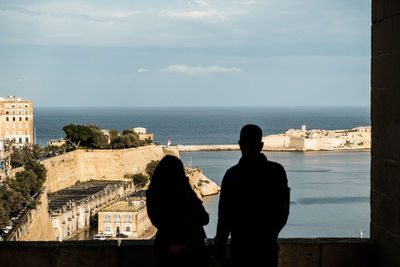 Rear view of people looking at sea against sky