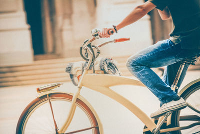 Low section of man riding bicycle on city street