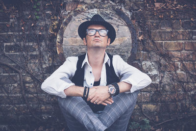 Portrait of young man standing against wall