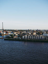 Aerial view of factory by river against clear sky during sunset