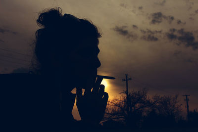 Silhouette boy against sky at sunset