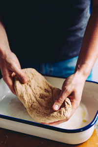 Midsection of person stretching dough in kitchen