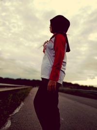 Full length of woman standing on road against sky