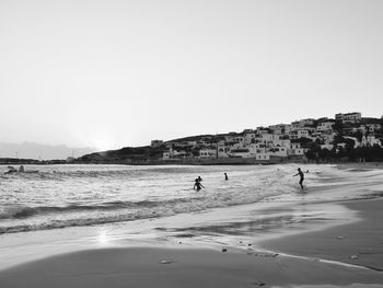 People on beach against clear sky