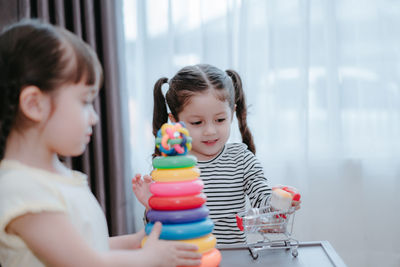 Sisters playing with multi colored toys at home