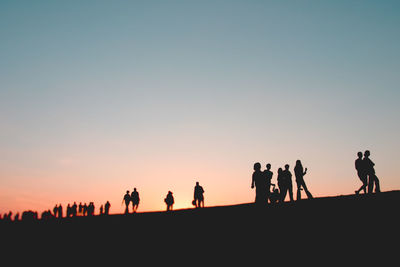 Silhouette people walking against clear sky during sunset