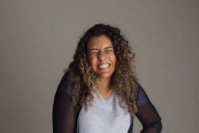 Portrait of young woman standing against gray background