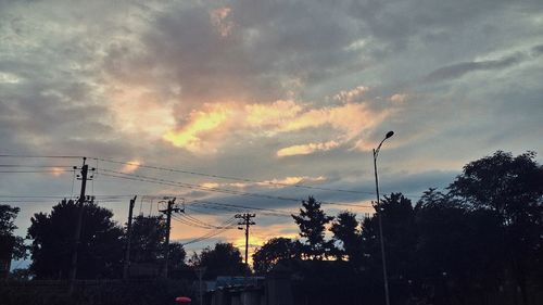 Low angle view of electricity pylon against cloudy sky