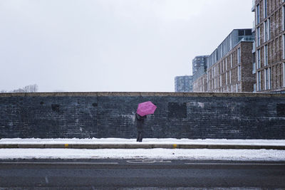Rear view of woman walking on wet road during rainy season