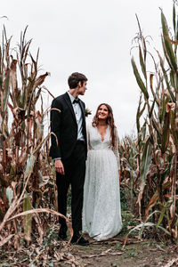 Couple standing by plants against sky