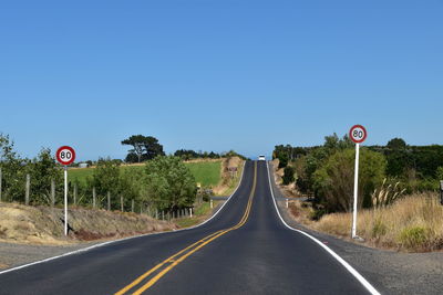 Road sign against clear blue sky