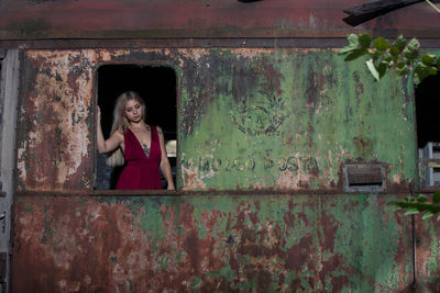 Full length of a smiling young woman standing against old wall