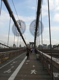 People walking on bridge in city against sky