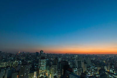 High angle view of city lit up at sunset