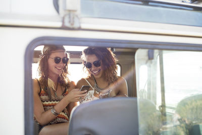 Friends using mobile phone in off-road vehicle seen through window