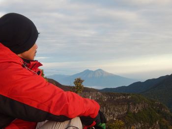 Side view of man looking at mountain against sky