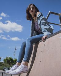 Low angle portrait of woman sitting against sky