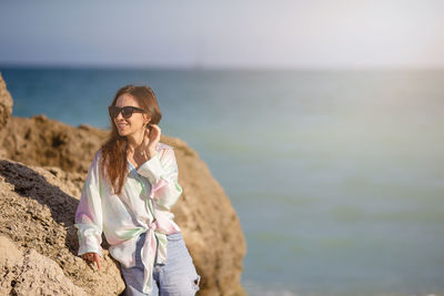 Portrait of young woman standing against sea