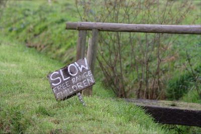 Close-up of wooden signboard on grass by footbridge