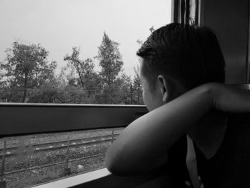 Side view of boy looking through window