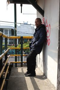 Portrait of young man standing against railing