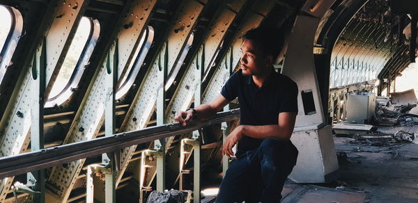 Young man looking through window in abandoned airplane