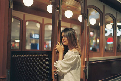 Woman standing at illuminated restaurant