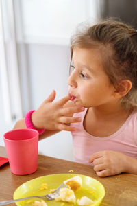 Little girl eating in the kitchen licking her fingers