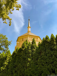 Low angle view of trees and building against sky