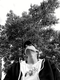 Low angle view of woman standing by tree against sky