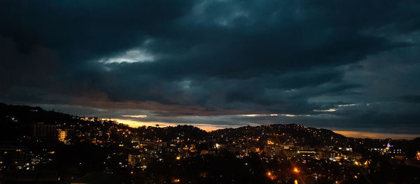 Aerial view of illuminated cityscape against dramatic sky