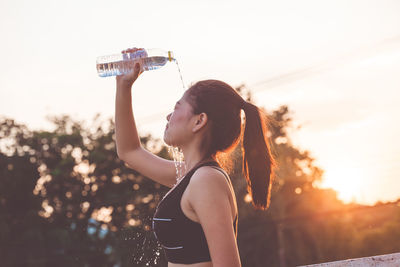 Young woman putting water on face during sunrise