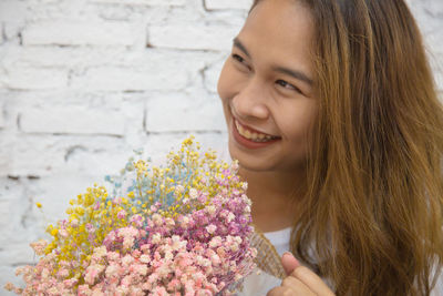 Portrait of smiling young woman against white flowering plants
