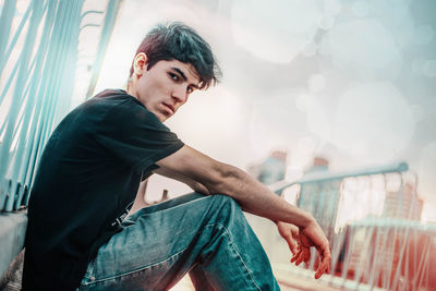 Portrait of young man standing against railing