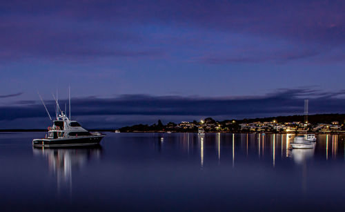 Sailboats moored in sea against sky at dusk