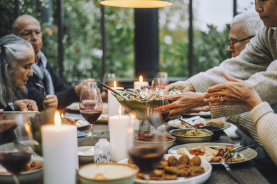 Senior woman serving salad to male and female friends during party