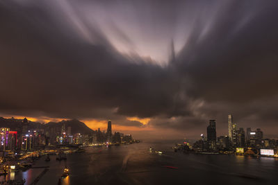 Illuminated buildings in city against sky at sunset