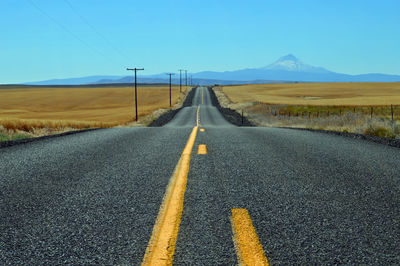 Empty road against a blue sky with mountain