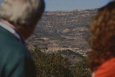 Rear view of man on rocky mountain against sky