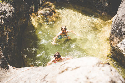 High angle view of brothers swimming in river amidst rock formations