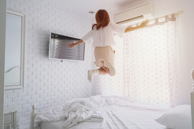 Rear view of woman on bed at home